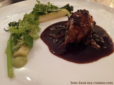 En plat, une caille reconstituée nappée de sauce aux morilles, et une garniture de légumes verts locaux.